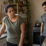 Louça na pia enquanto um casal enfrenta um momento de tensão no relacionamento.